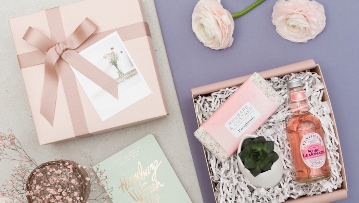 collection de produits cosmétiques et décoratifs dans une boîte cadeau à emballage diy en papier rose pastel avec ruban