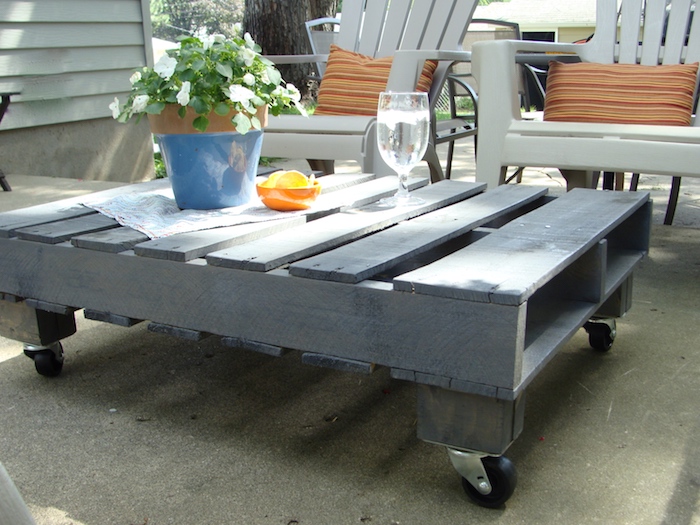 exemple de table basse en palette facile à faire avec une palette repeinte en gris et roulettes montées, chaises de jardin