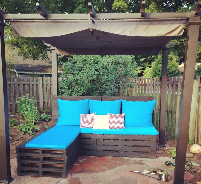 coussin salon de jardin palette bleu, canapé d angle palettes et pergole en bois et métal dans un jardin
