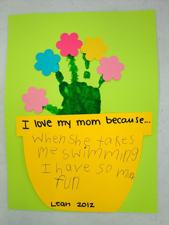 un pot de fleur en papier jaune avec message pour maman et empreinte de main verte, arbre avec des fleurs en papier colorées