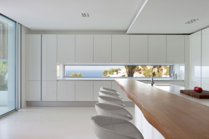 intérieur design moderne et épuré avec meubles blancs sans poignées et un modèle d'ilot central en comptoir de bois massif