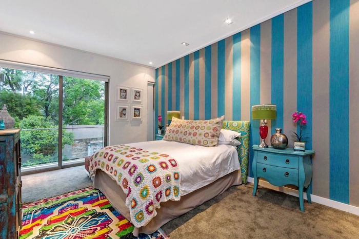 grande chambre enfant avec baie vitrée, tapisserie gris et bleu et tapis coloré du pérou