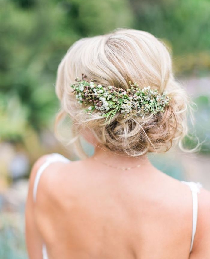 chignon mariage boheme chic style flou accessoirisé de fleurs naturelles, cheveux blond bouclés