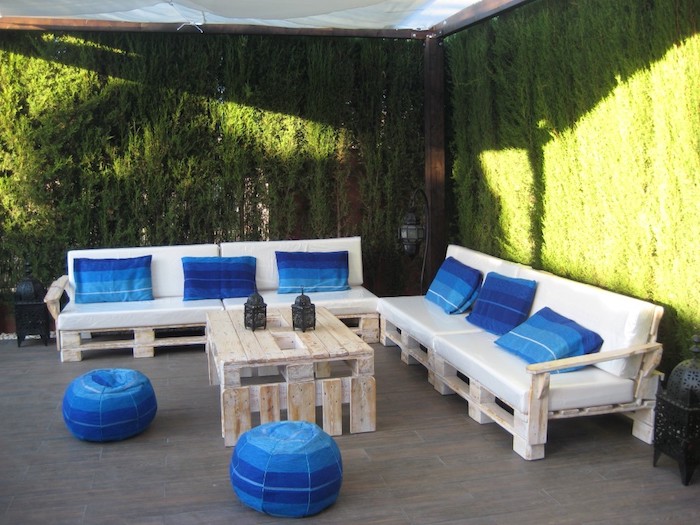 meubles de jardin en palettes canapés en palettes blanchis avec coussins d assise blancs et coussins décoratifs et poufs bleus, table basse palette, mur végétal