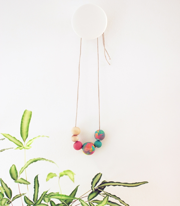 un collier avec des perles en bois colorées accroché sur un mur, diy fete des meres facile pour fabriquer un accessoire femme