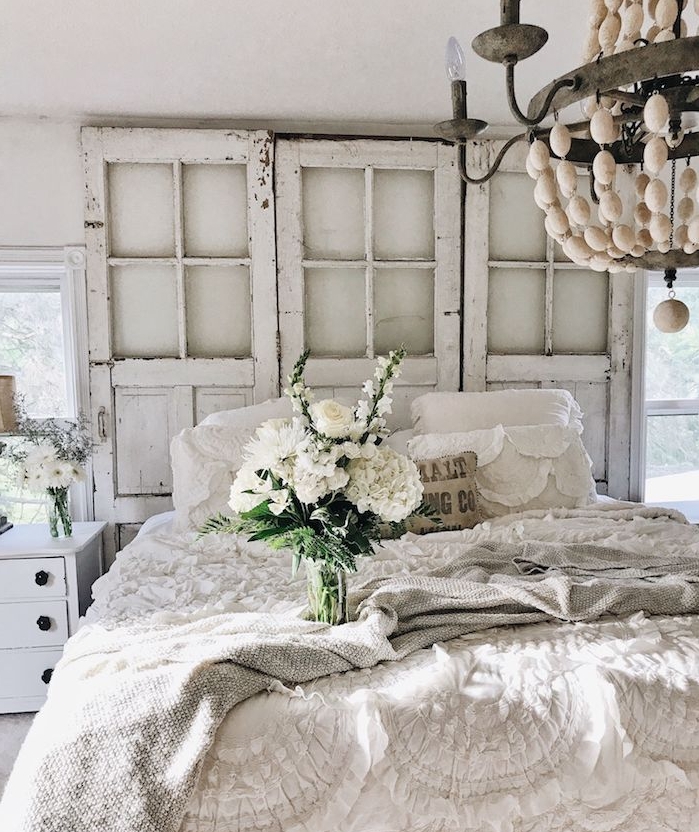 portes en bois recyclées aspect brut avec linge de lit blanc et plaid gris, bouquet de fleurs blanches, lustre élégant, style campagne chic