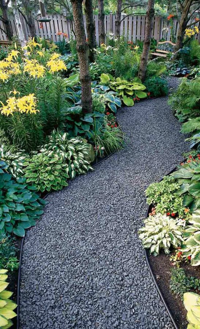 petit chemin avec des pierres noires entre les plantes vertes et jaunes, jardin paysager, coin relax zen, arbrisseaux disposés en zig-zag 