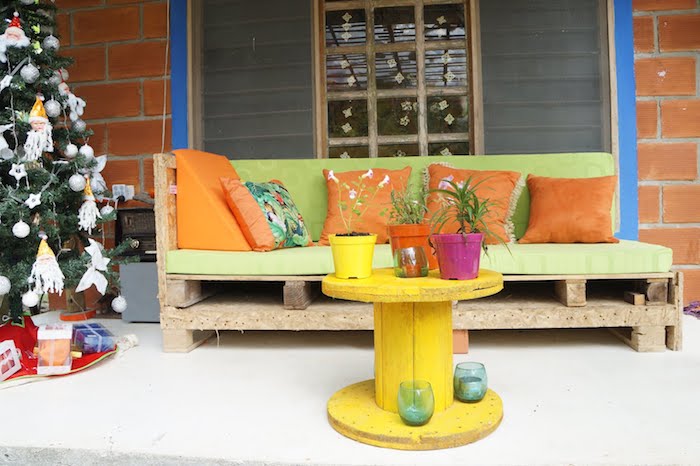 table en touret, coussin salon de jardin palette vert pistache et coussins décoratifs orange, touret jaune et pots de fleurs