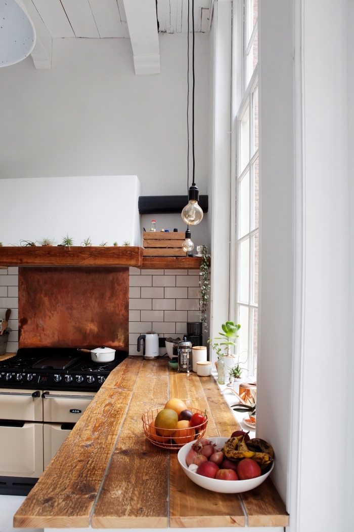 déco de style rustique dans une cuisine aux murs blancs avec plafond à poutres apparentes et crédence à carrelage briques blanches