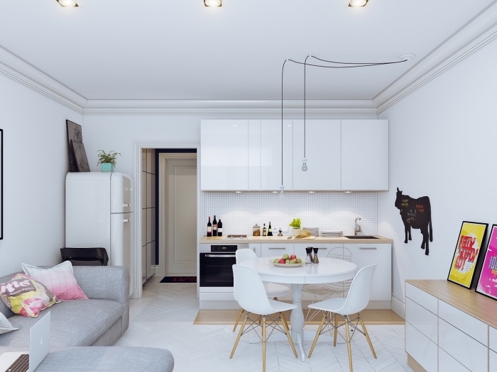 modèle de petite cuisine blanc et bois avec table ronde et chaises dans un studio aménagé avec coin canapé-lit