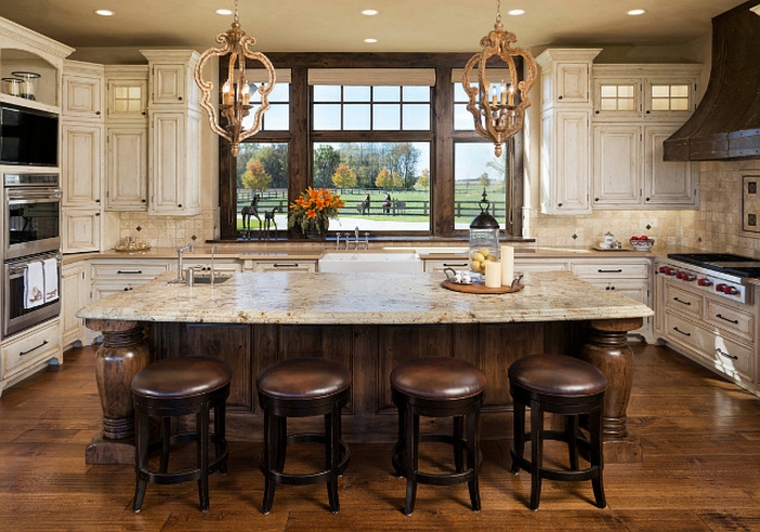 jolie cuisine avec ilot central table, petits tabourets en cuir, sol en bois, chandeliers rustiques modernes, cabinets blancs suspendus