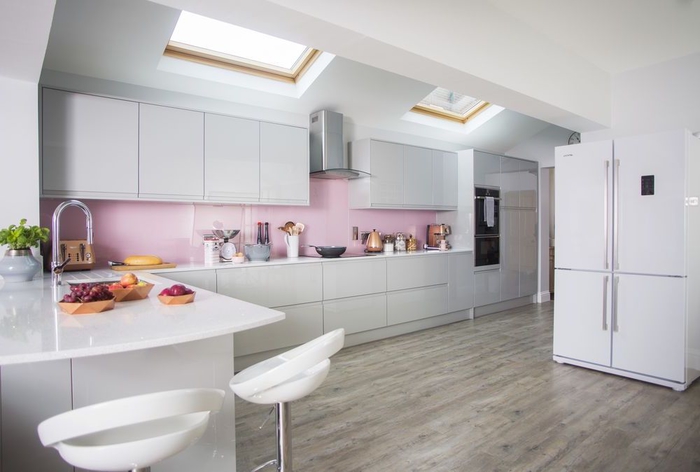 cuisine gris laqué lumineuse et douce associant des meubles de cuisine au design épuré à une crédence rose poudré à finition brillante