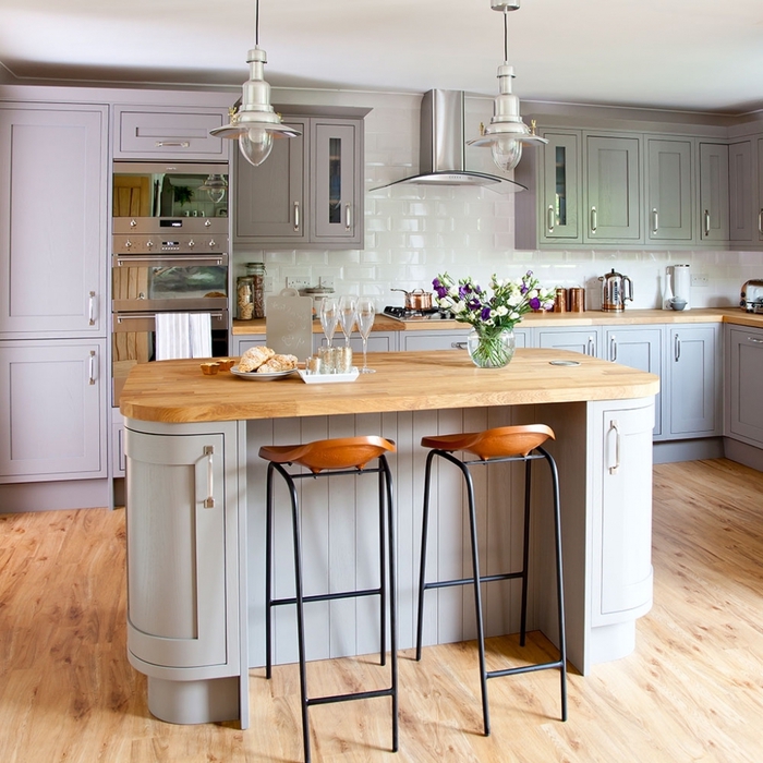 une cuisine grise et bois de style bistro qui associe des meubles gris et rose poudré avec un plan de travail en bois clair et un mur en fausses briques blanches