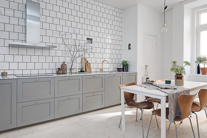 quelle couleur pour une cuisine d'ambiance nordique, design simple et épuré d'une cuisine grise sans meubles hauts qui affiche un joli carrelage mural blanc
