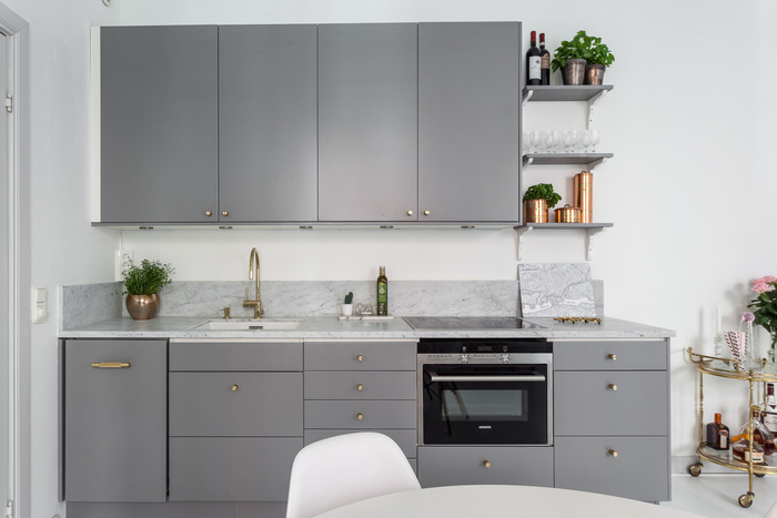 cuisine grise moderne et minimaliste qui associent des meubles de cuisine gris mat aux poignées dorées et à un comptoir en marbre pour une allure chic et contemporaine