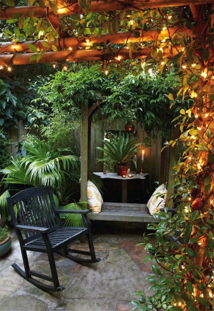 idee amenagement jardin devant maison, chaise basculante noire en bois, pergola avec des plantes vertes, ambiance cool relaxante 