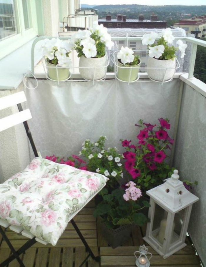 chaise en bois blanc et métal noir, lanterne en métal blanc, pots avec des violettes blanches et fuchsia, amenagement petite terrasse, decoration terrasse exterieur, sol avec lame bois a emboîter