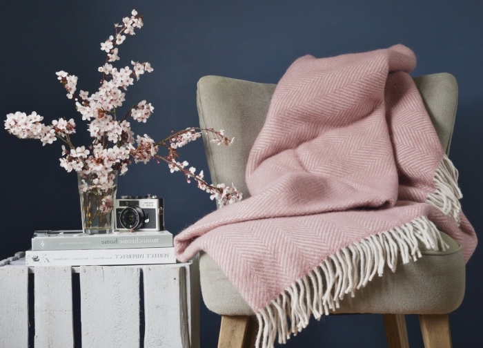 objets de décoration d'intérieur de style cozy avec une chaise grise et plaid rose pastel à franges blanches