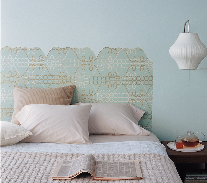 idée de tête de lit papier peint en bleu et beige sur un mur bleu, linge de lit rose et blanc, table de nuit bois, lampe blanche