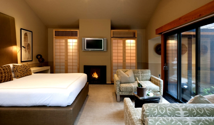 déco de chambre feng shui, lit plateforme en cuir, cheminée murale, fauteuils en textile