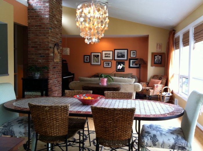 grande table ovale, chaises tressées, plafonnier impressionnant, peinture murale jaune et orange, peinture tendance salon