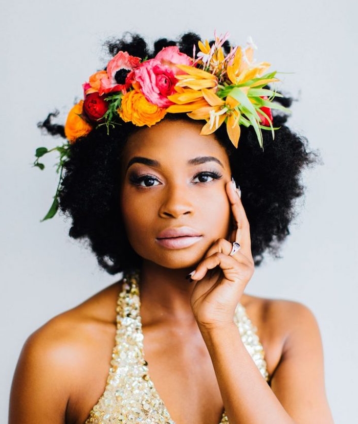 femme afro avec cheveux accessoirisés d une couronne de fleurs colorées, coiffure cheveux crépus exemple et robe de mariée à pailelttes