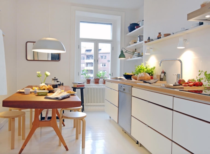 exemple de cuisine blanche aménagée avec table à magner et meubles blancs sans poignées, modèle de rangement vertical