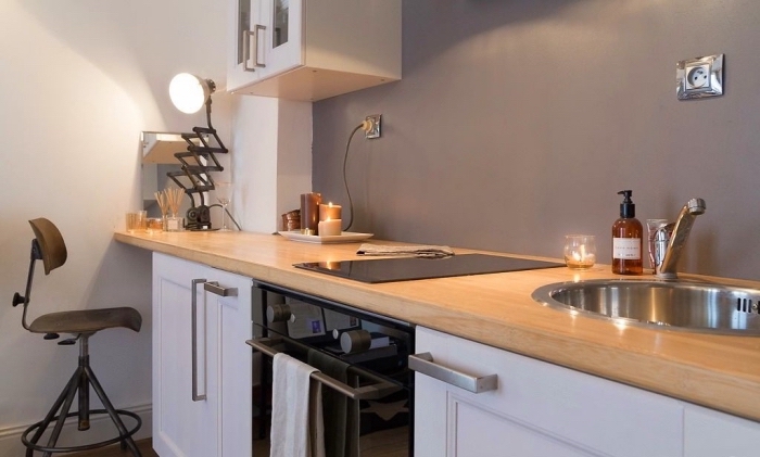 modèle de cuisine grise et bois avec pan de mur de nuance gris clair combiné avec armoires bas en blanc et four noir