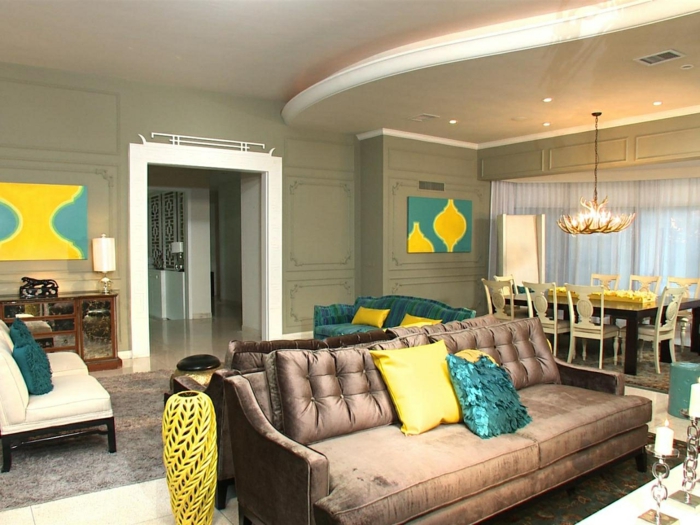 séjour contemporain, canapé en couleur taupe, plafond suspendu ondulant, coussins déco jaunes et bleus