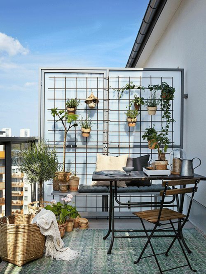 balcon fleuri, mur porte-plante avec une dizaine de pots avec des fleurs, carrelage motifs orientaux en vert et blanc, meubles pliables de jardin IKEA, gros panier de paille tressée