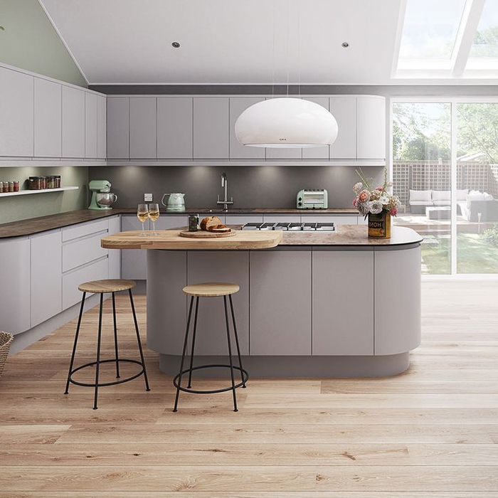 une cuisine moderne grise et vert de gris aux lignes épurées sans poignées, équipée d'un îlot central design à comptoir en bois