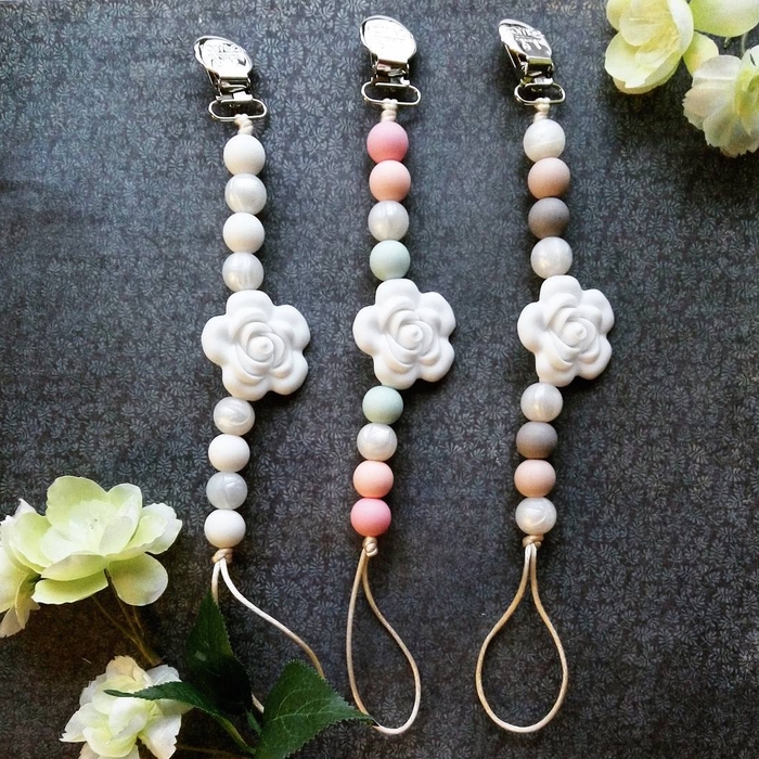 modèle d'attache tétine personnalisée raffiné et doux réalisé avec des perles en tons pastel, décoré d'une jolie fleur blanche au milieu de la chaîne