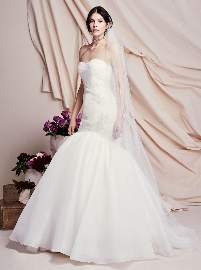 modèle de robe de mariée sirène avec un bas évasé et un hait blanc avec de petites décorations et voiles blanche longue