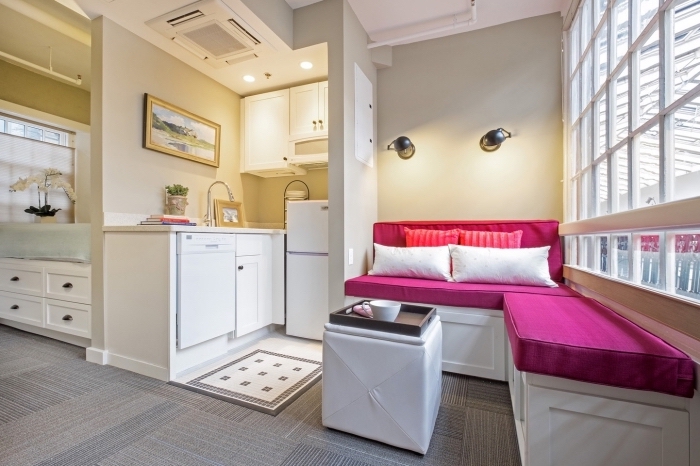 aménager un petit appartement aux murs beige avec mobilier de couleur vibrante en forme de canapé d'angle rose fuchsia 