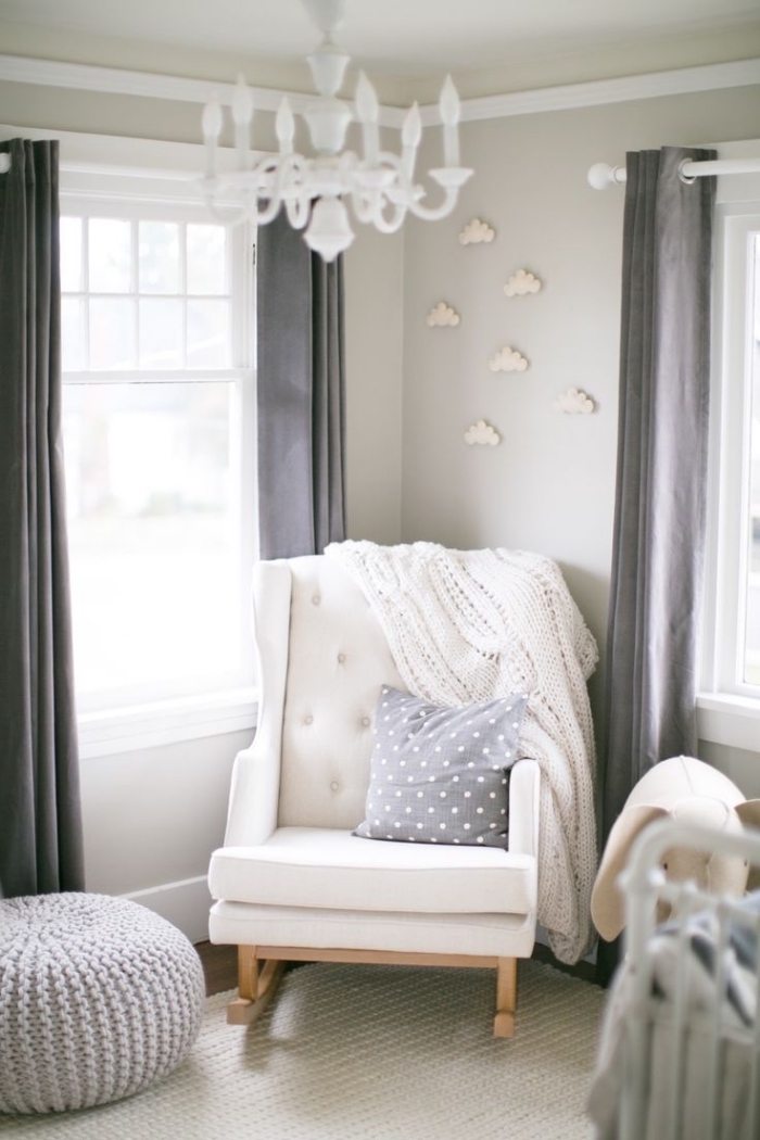 coin de repos dans une pièce nouveau-né aux murs beige avec un fauteuil à dos boutonné blanc et pieds de bois