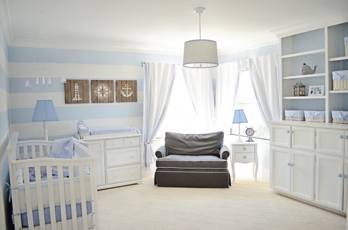 exemple de design bicolore en blanc et bleu clair dans une pièce de nouveau-né avec rideaux longs et meubles de bois blancs