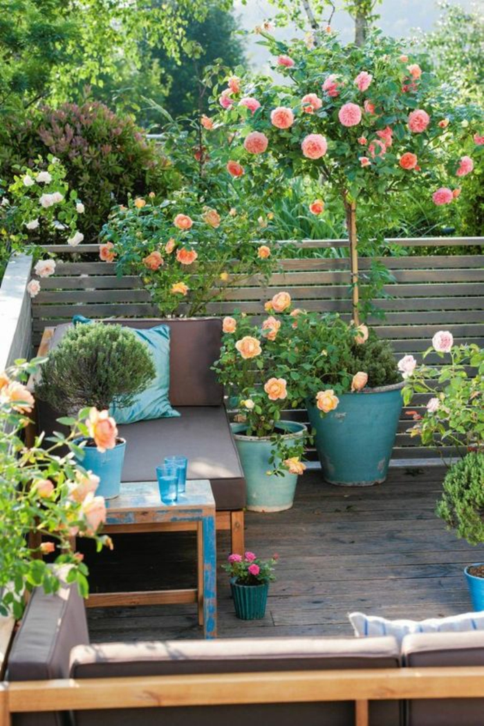 jardin deco, déco jardin récup, amenagement jardin, sceaux en bleu canard avec des roses, canapé avec des coussins marron, petit espace fleuri entouré de cintre 