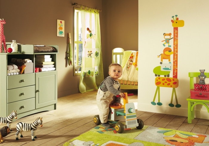 design intérieur dans une pièce enfant aux murs taupe et jaune pâle avec dessin girafe et plancher de bois