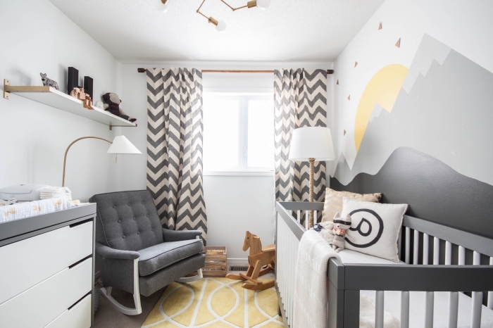 design de la chambre bébé en couleurs blancs et noirs de style minimaliste avec accessoires de bois et aux accents en gris