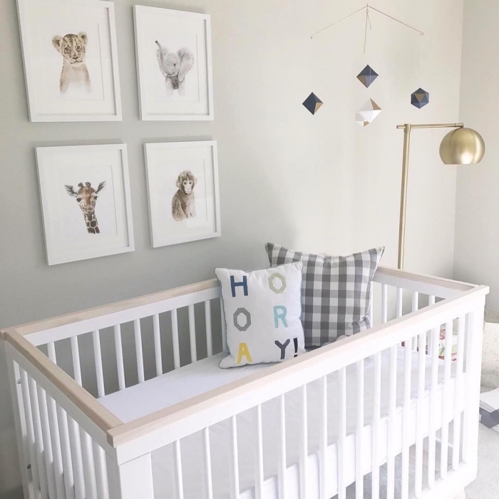 modèle de mobile bébé à design cristaux au-dessus d'un lit bébé blanc et bois avec coussins décoratifs et lampe sur pied dorée