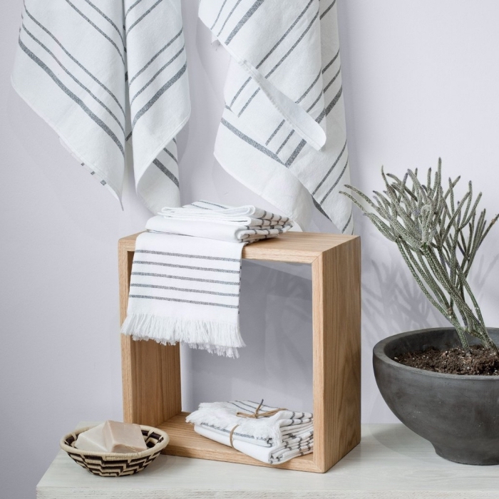 arrangement de salle de bain de style relaxante avec un set de serviette de bain en blanc et noir sur un meuble de bois clair