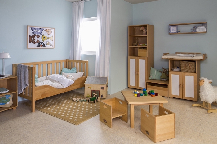 modèle de deco chambre enfant aux murs en bleu pastel et meubles nouveau-né de bois clair sur plancher beige