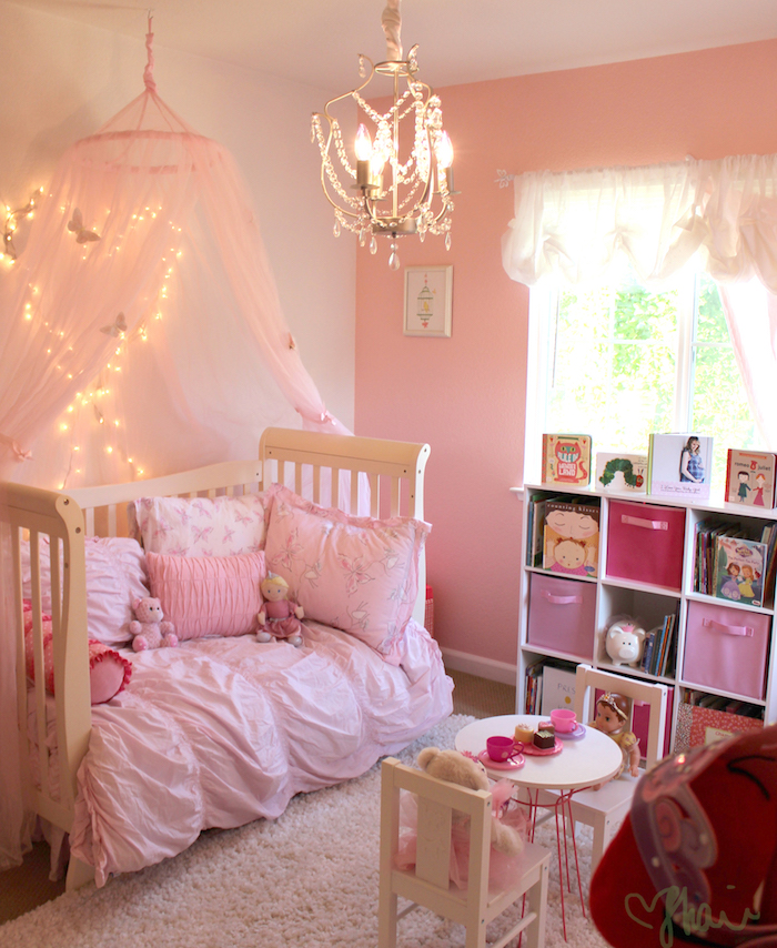 chambre bébé petite fille avec lit à barreaux en bois semi ouvert et déco rose 
