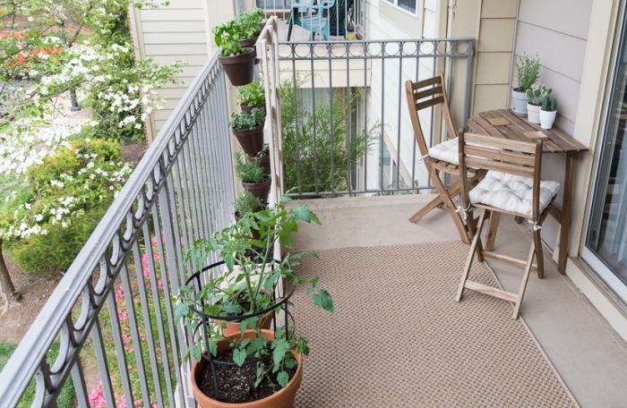 aménagement espace extérieur d'appartement avec tapis beige et mobilier de bois, cultivation légumes en pots