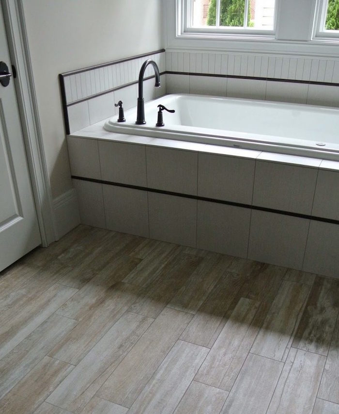 decoration de salle de bain blanche avec parquet faux bois beige clair et baignoire avec faience