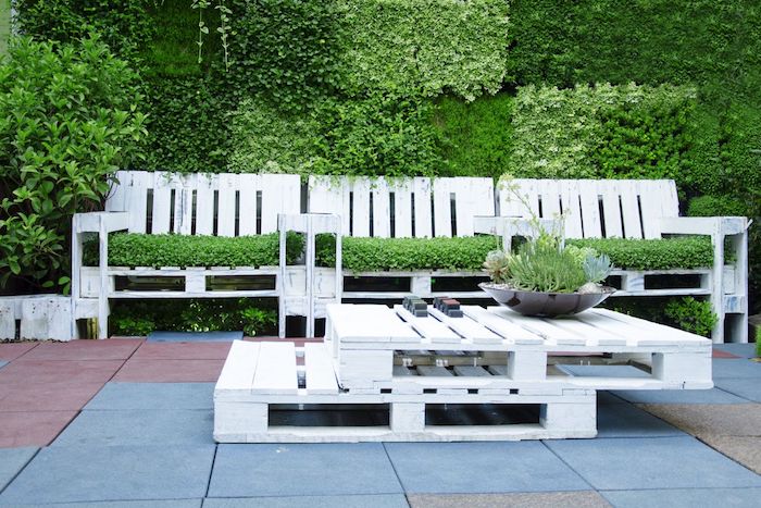 modèle de salon de jardin palette avec un canapé en palette couvert de gazon, table basse en palettes blanches superposées, mur végétal extérieur