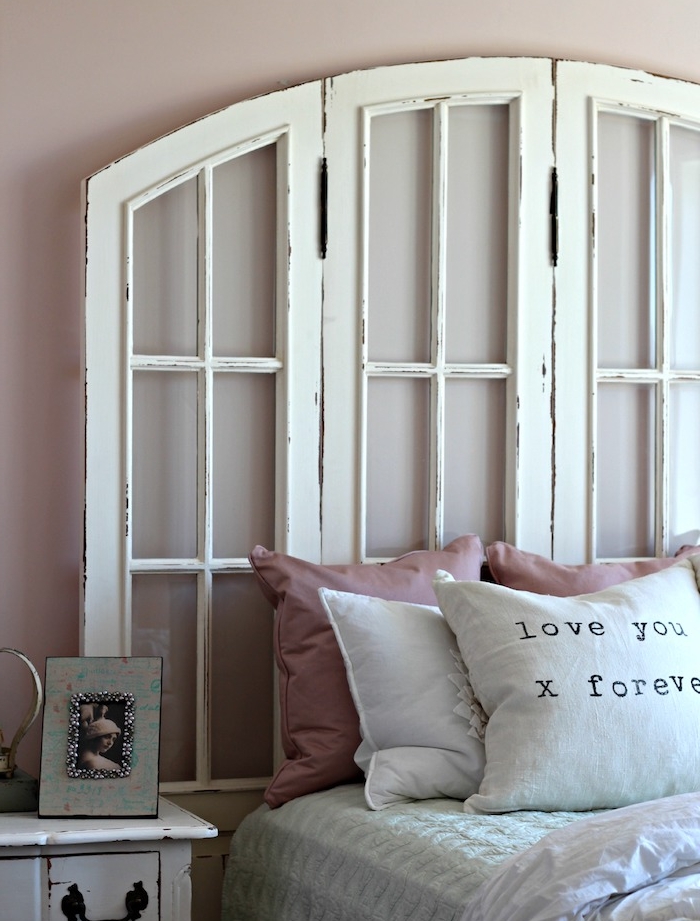 volets de fenetres blancs recyclés en blanc, linge de lit blanc avec coussins décoratifs rose, table de nuit vintage