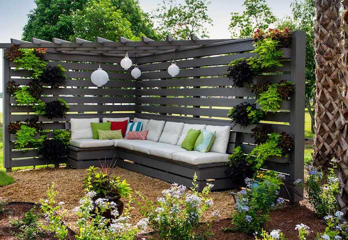 pergola moderne avec mur vertical de plantes et un canapé gris avec coussin d assise blanc et coussins décoratifs colorés, plantes de jardin