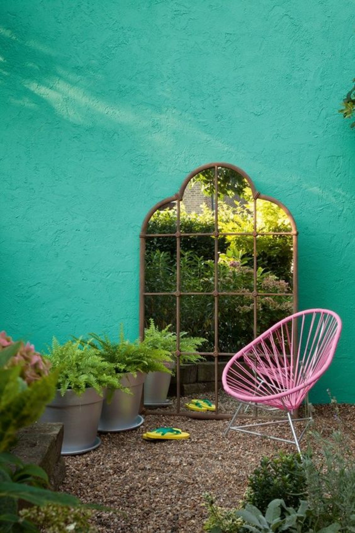 miroir posé par terre dans un coin de jardin, grands sceaux transformés en pots avec des plantes vertes, fauteuil rose en métal, déco jardin récup 