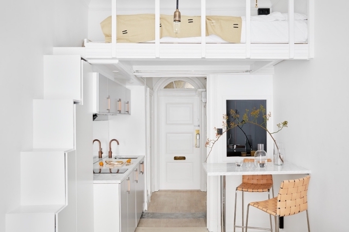 idée aménagement studio avec un lit mezzanine et petite cuisine blanche équipée d'un coin à manger avec ilot et chaises